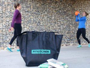 2 youg girls playing with a ball in the background of Fitkitchen delivery bag 