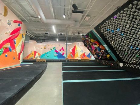 Indoor climbing facility. Various hand holds looking like rocks. One wall slanted inwards.