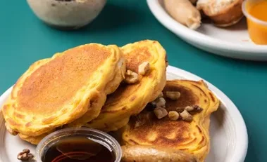 Breakfast spread with pancakes, bacon, and eggs on a table