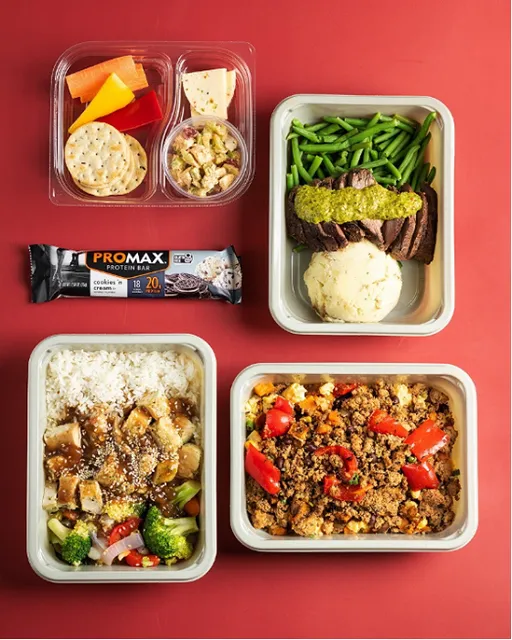 A variety of meal prep containers on a red surface