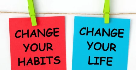 Two notes with motivational messages are clipped to a string. The red note reads Change Your Habits and the blue note reads Change Your Life