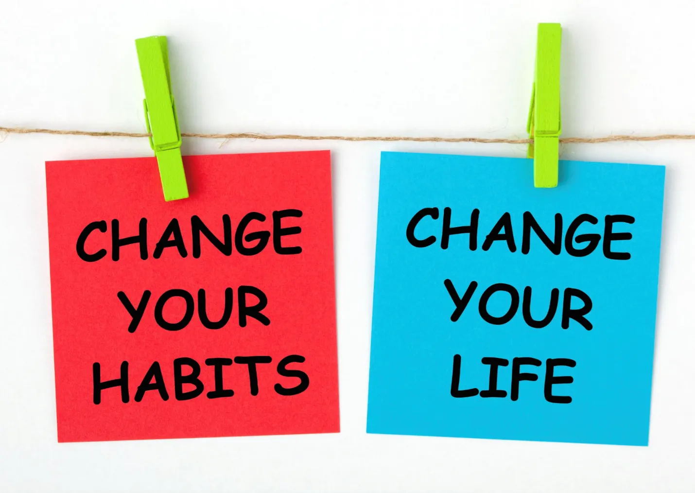 Two notes with motivational messages are clipped to a string. The red note reads Change Your Habits and the blue note reads Change Your Life