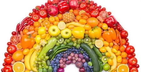 A variety of fruits and vegetables arranged in a rainbow pattern on a white background