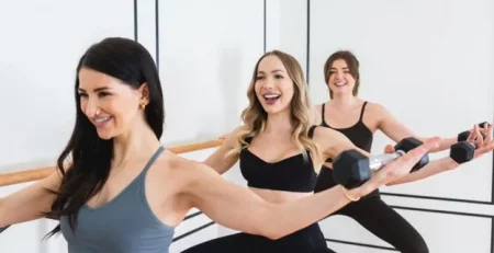 Three people performing a workout with dumbbells in a fitness studio